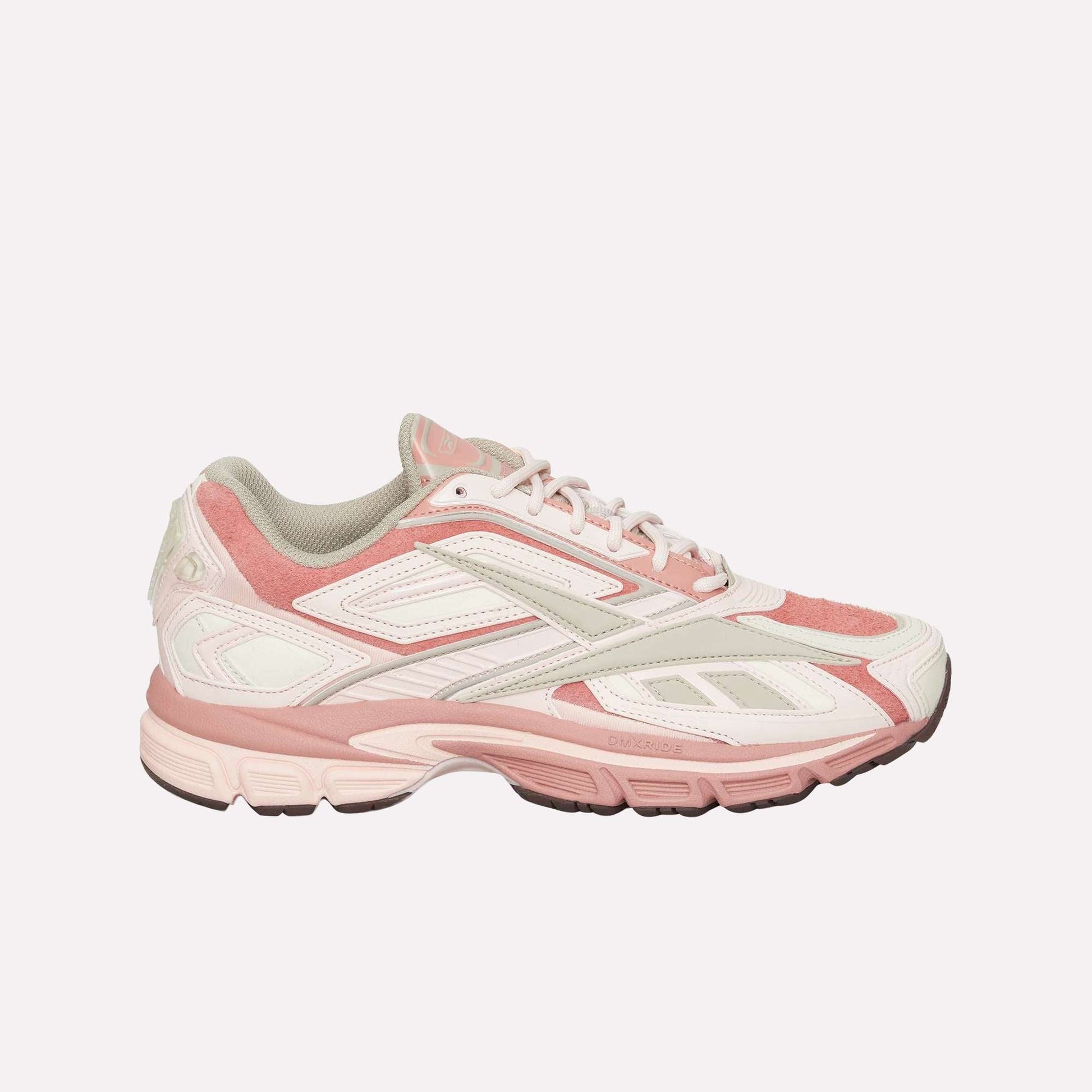The Reebok Premier Road Ultra, a pink and white sneaker with suede and mesh details, dual-density midsole, chunky sole, and white laces, is shown against a plain white background.