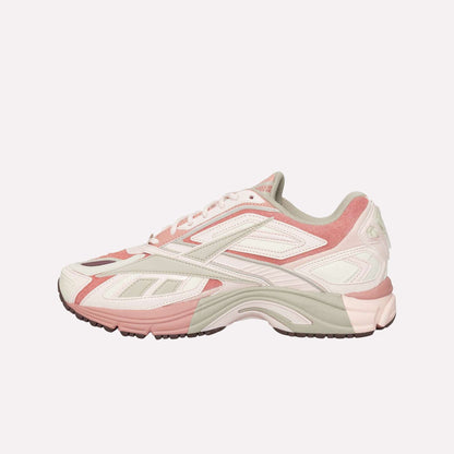 The Reebok Premier Road Ultra is a stylish running sneaker in pink, white, and beige, seen from the side. It features a dual-density midsole, textured rubber sole, and layered details on the upper.