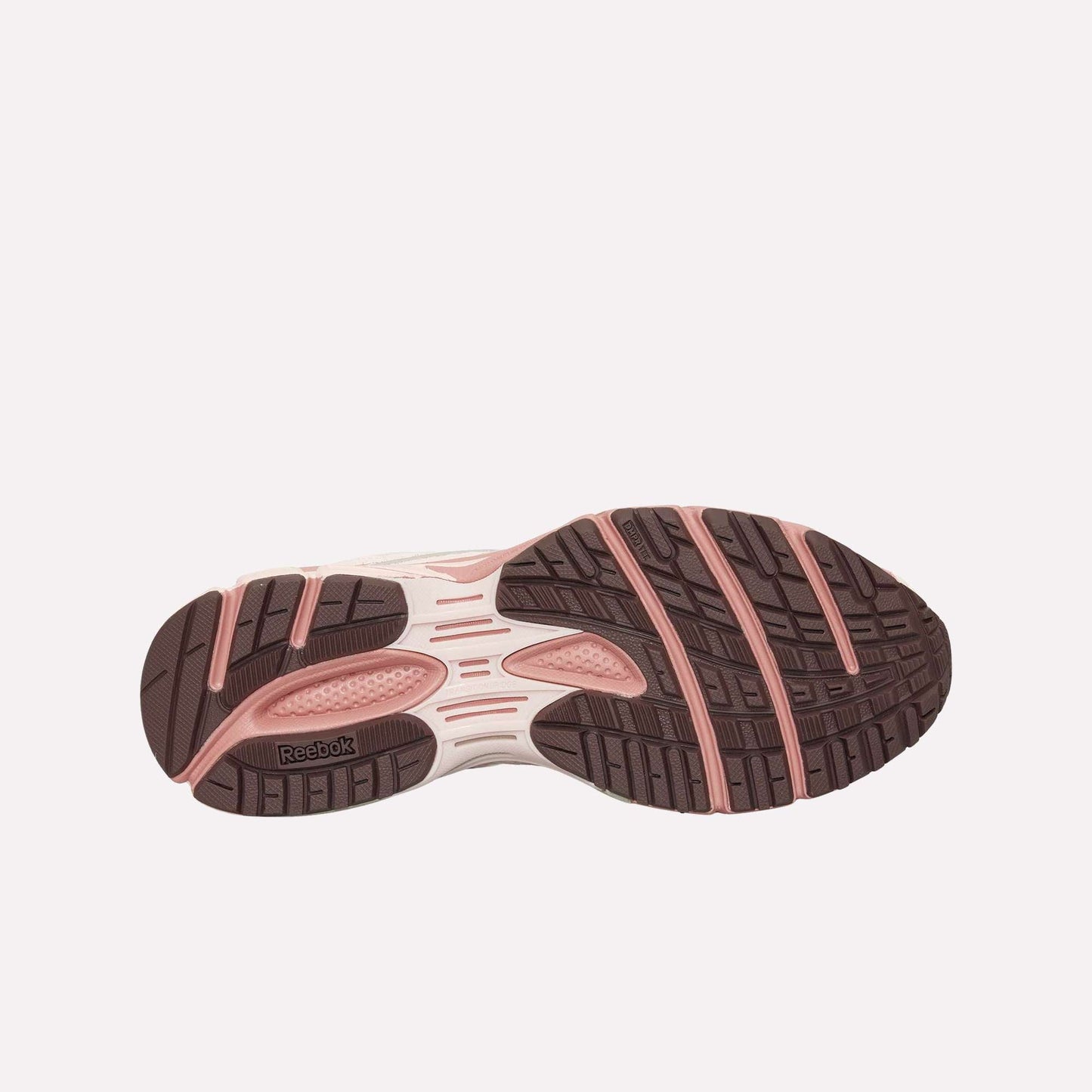 The image shows the outsole of the Reebok Premier Road Ultra, featuring pink and brown rubber with a textured tread for grip. The Reebok logo appears near the heel, alongside a dual-density midsole for comfort.
