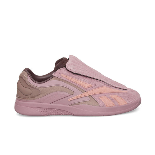 The Reebok Hammer Pro Ltd features a mauve and pink suede upper, a textured layered design, a large padded flap covering the laces, and a thick rubber sole with a bold pattern.