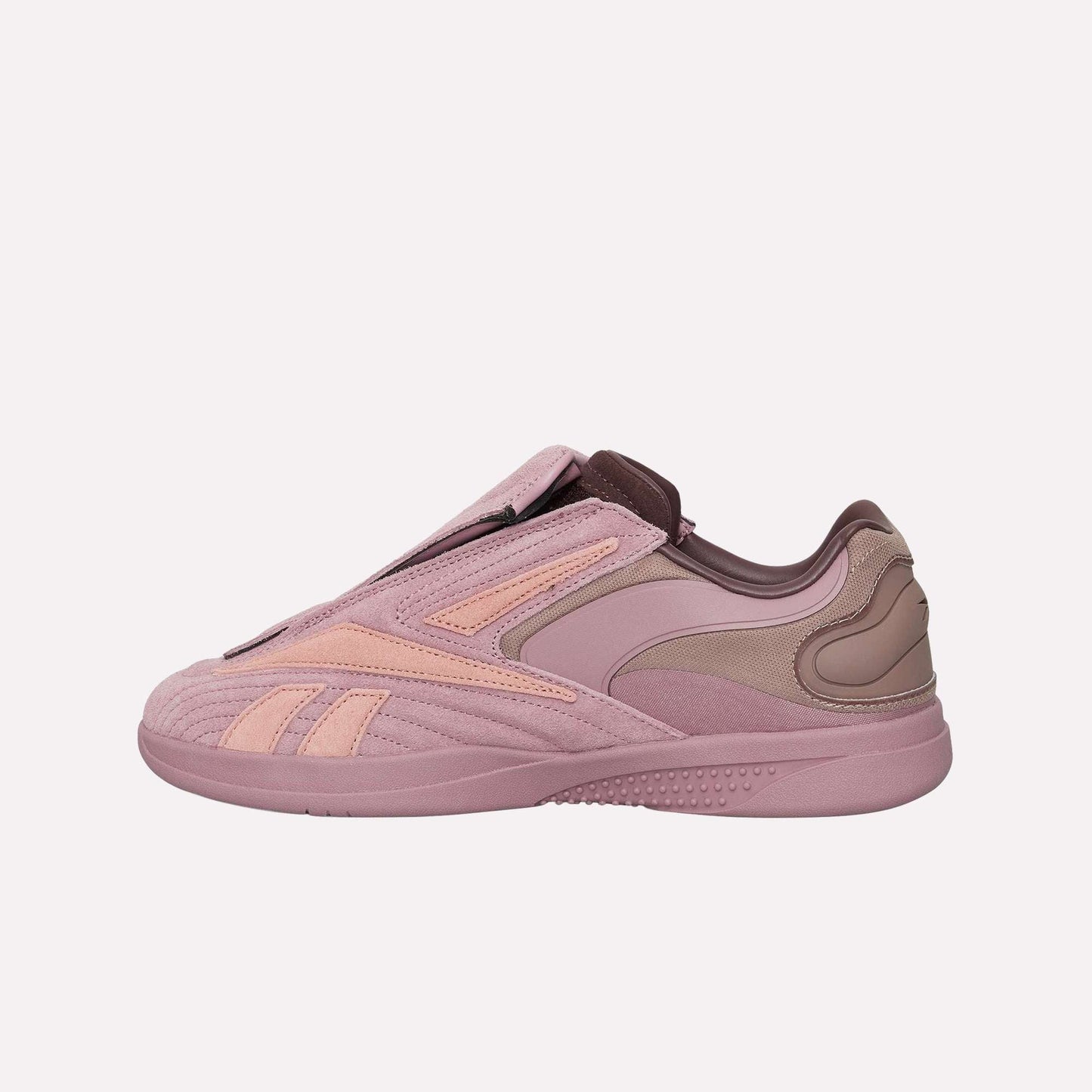 A side view of the Reebok Hammer Pro Ltd shows its pink and mauve suede upper, sleek curved paneling, subtle branding, and hidden lacing for a minimalist look.