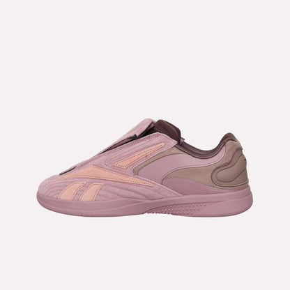 A side view of the Reebok Hammer Pro Ltd shows its pink and mauve suede upper, sleek curved paneling, subtle branding, and hidden lacing for a minimalist look.