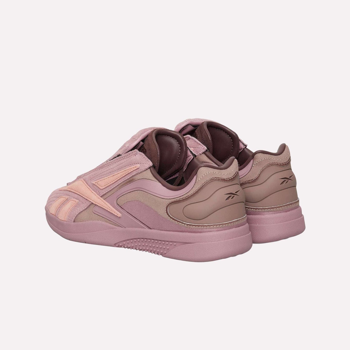 The Reebok Hammer Pro Ltd sneakers in mauve and light pink feature a suede upper, layered materials, a branded heel, and a durable rubber sole, all showcased at an angle for maximum style impact.