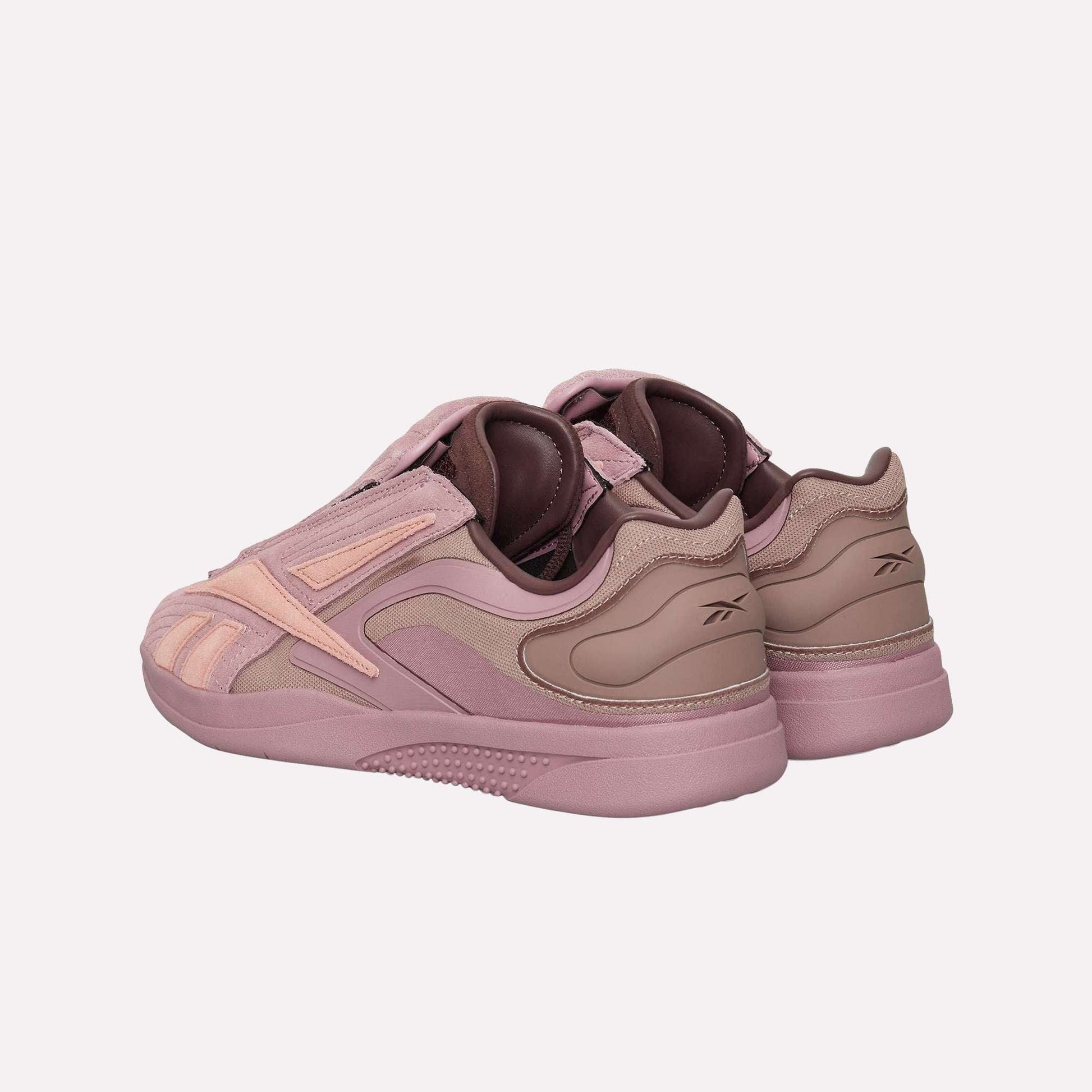 The Reebok Hammer Pro Ltd sneakers in mauve and light pink feature a suede upper, layered materials, a branded heel, and a durable rubber sole, all showcased at an angle for maximum style impact.