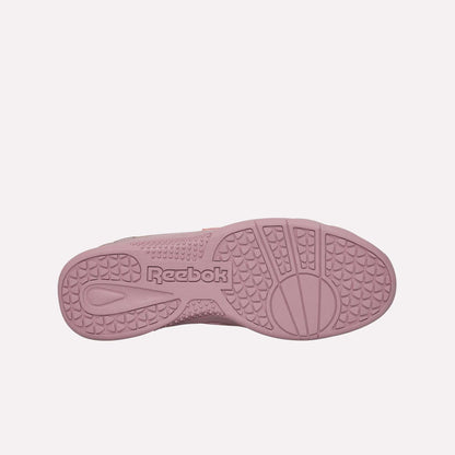 The image shows the sole of the Reebok Hammer Pro Ltd sneaker in pink, with textured grip patterns and a central Reebok logo. Its durable rubber sole emphasizes both quality and style.
