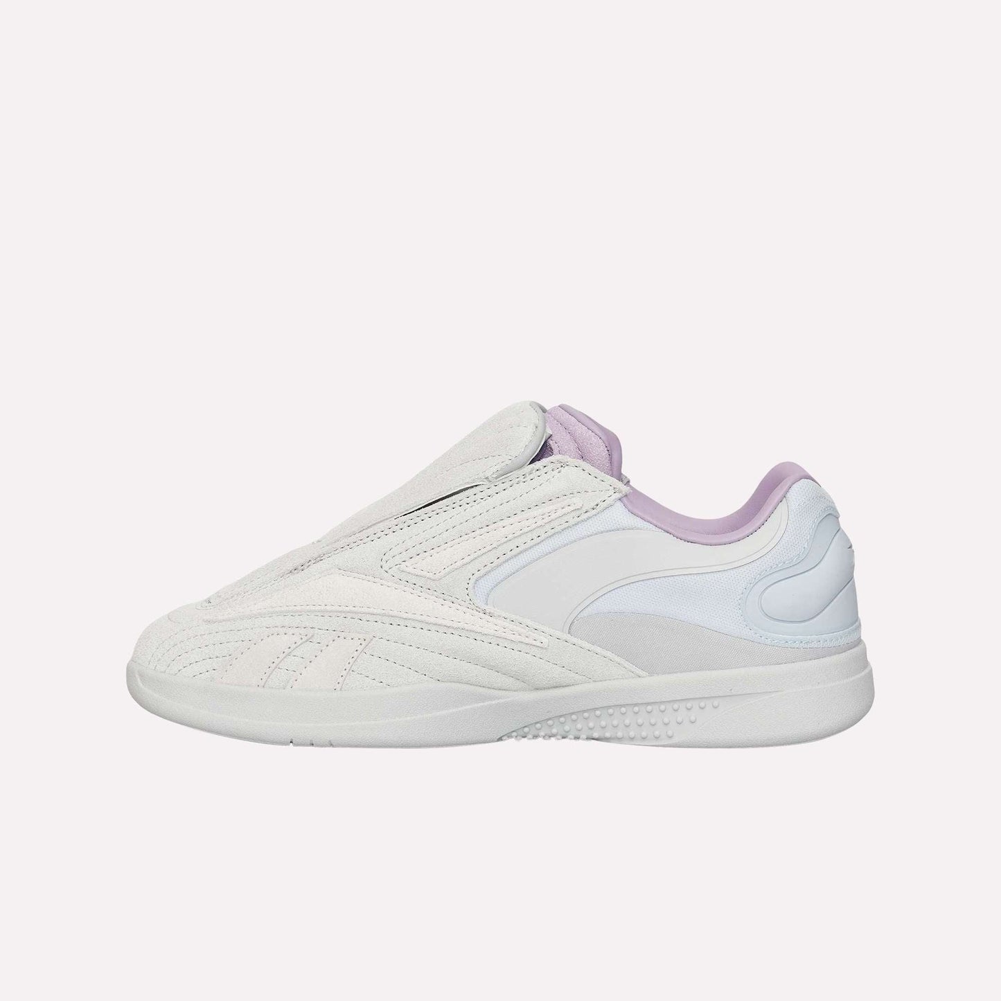 The Reebok Hammer Pro Ltd is a white slip-on sneaker with light grey and pale lavender accents, featuring a durable rubber sole, suede upper, textured sole, and curved stitching details on the side.