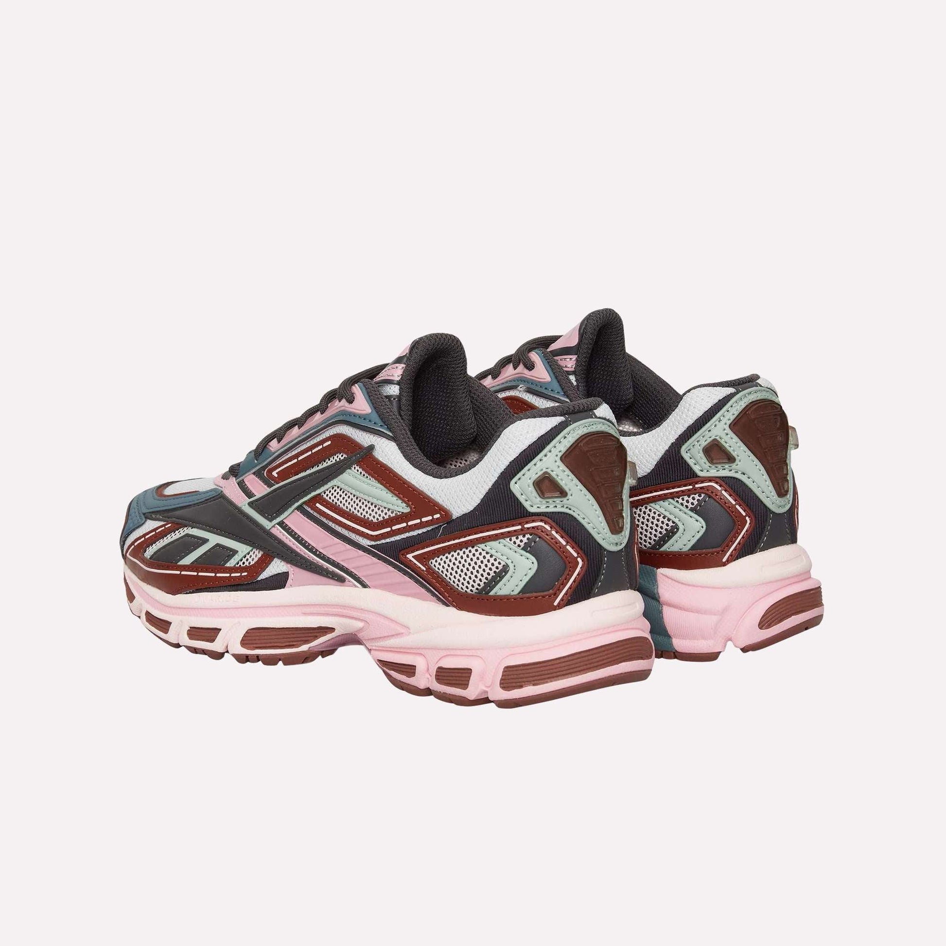 The Reebok Premier Road Ultra sneakers, shown from back and side angles, feature a blend of pink, burgundy, gray, and white with mesh and synthetic materials inspired by archival running designs.