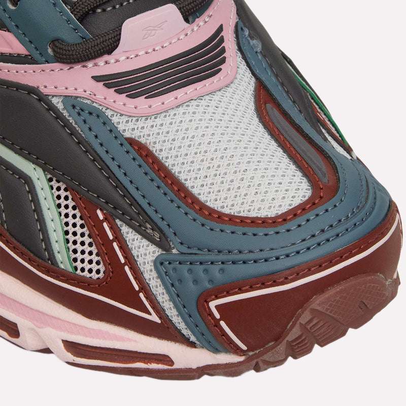 Close-up of the Reebok Premier Road Ultra, a retro running sneaker with blue, red, pink, and black layered panels on white mesh, detailed textures and stitching, and a dual-density midsole for comfort.